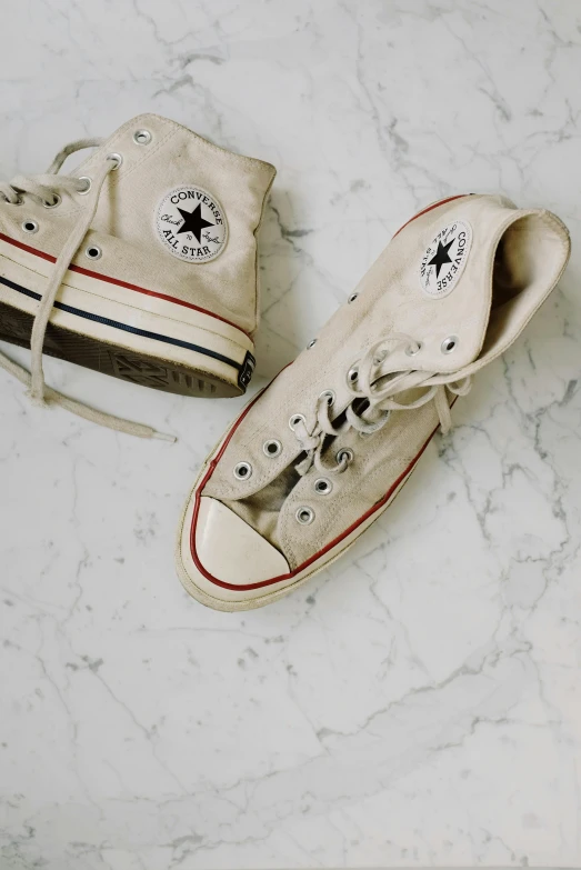 a pair of shoes sitting on top of a marble floor, inspired by Elsa Bleda, trending on pexels, converse, cream and white color scheme, 1970's, made of marble