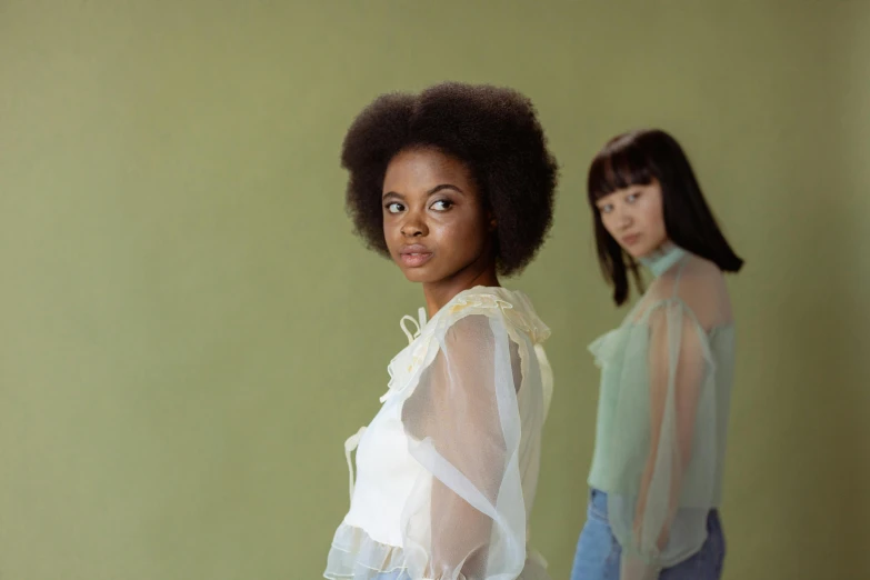 a couple of women standing next to each other, an album cover, by Winona Nelson, pexels contest winner, cream colored blouse, mixed race, pale green glow, concept photoset