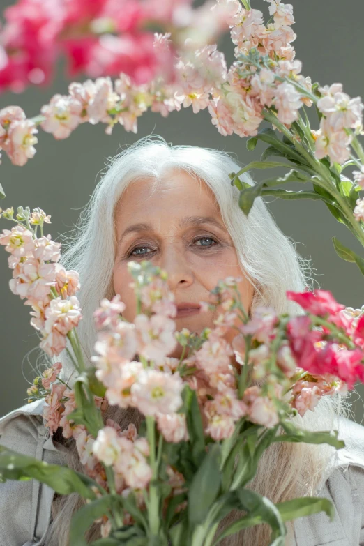 a woman holding a bunch of flowers in front of her face, an album cover, inspired by Grethe Jürgens, renaissance, long grey hair, portrait 6 0 - year - old woman, made of flowers, 2022 photograph