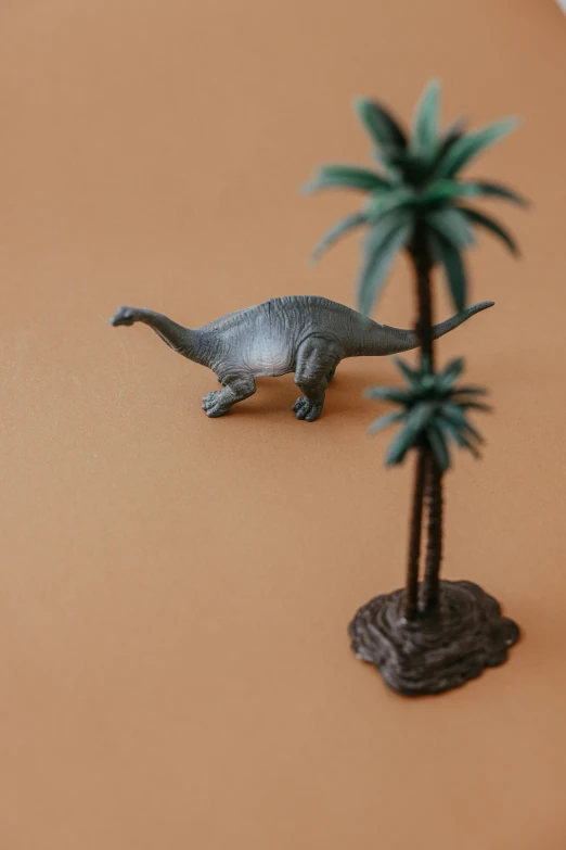 a figurine of a dinosaur next to a palm tree, by Andries Stock, trending on unsplash, flat lay, animation, pvc figurine, indoor picture