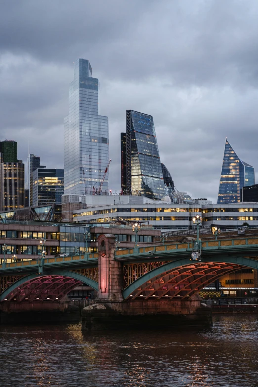 a train traveling over a bridge over a river, by Jay Hambidge, unsplash contest winner, modernism, with tall glass skyscrapers, london architecture, evening lighting, white buildings with red roofs