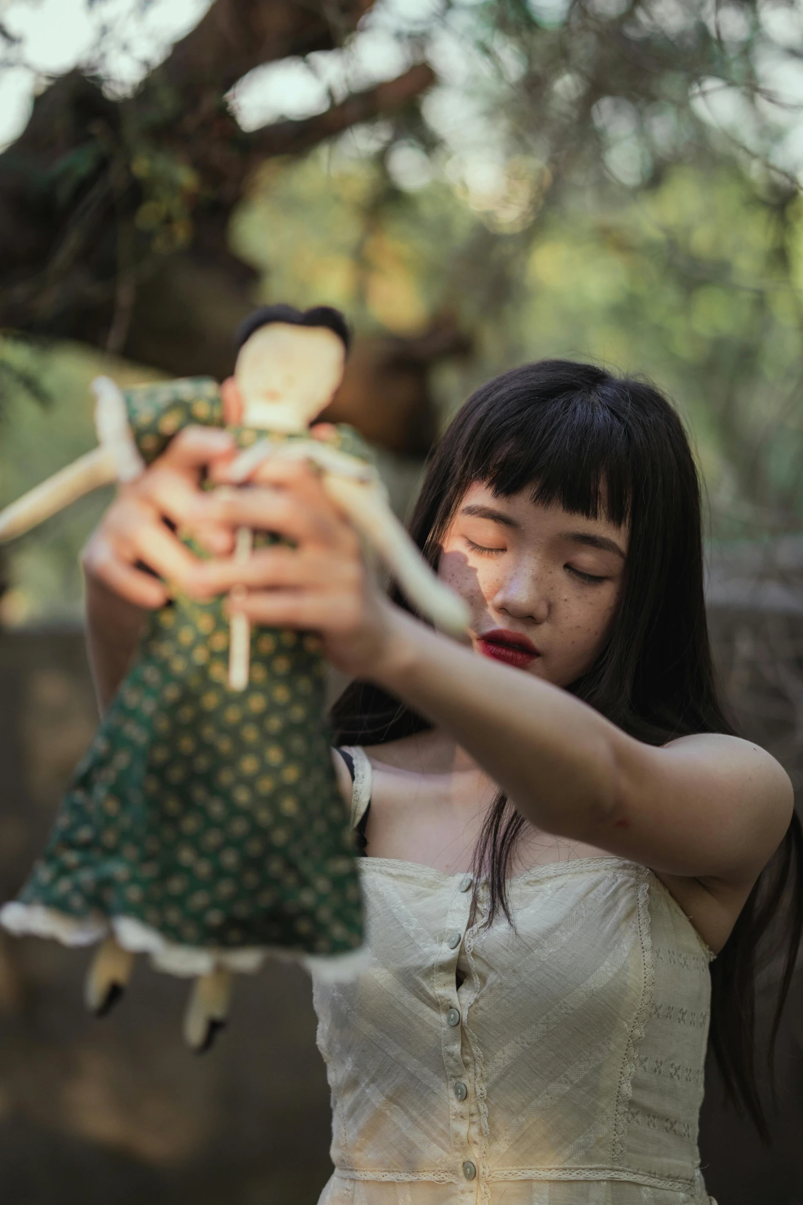 a woman in a white dress holding a doll, unsplash, magical realism, young asian girl, zeen chin and farel dalrymple, puppets, wooden