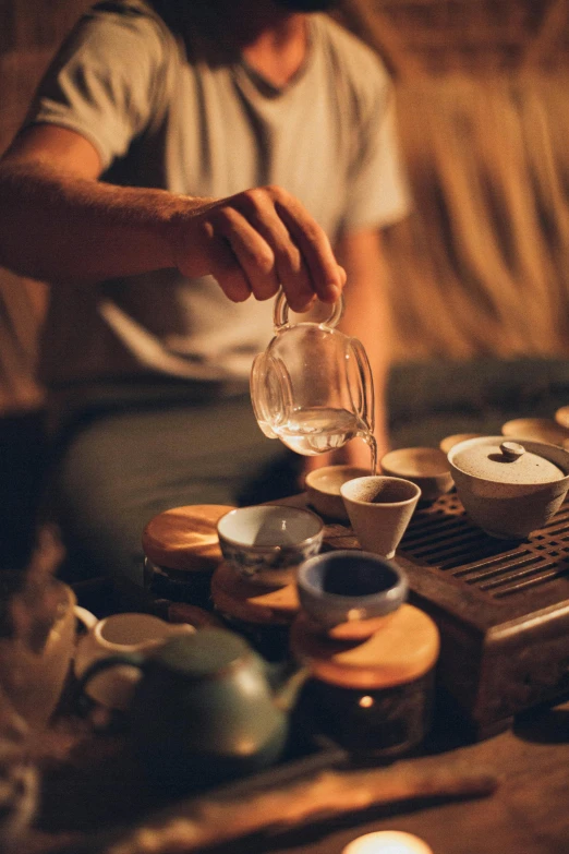 a person pouring tea into a cup on a table, a still life, by Daniel Lieske, trending on unsplash, square, night, song dynasty, 15081959 21121991 01012000 4k