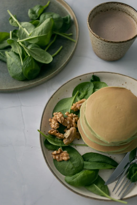 a plate topped with a stack of pancakes next to a cup of coffee, by Andries Stock, unsplash, steamed buns, salad, green hue, studio photo