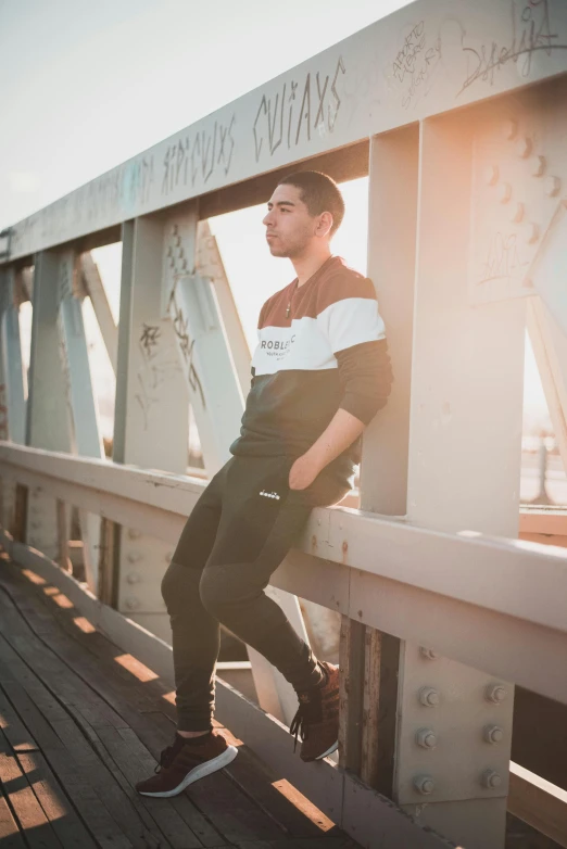 a man standing on top of a wooden bridge, trending on unsplash, happening, wearing a track suit, white and black clothing, leaning on the wall, hispanic
