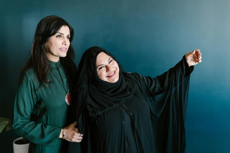 a couple of women standing next to each other, hurufiyya, ameera al taweel, profile image, triumphant pose, shohreh aghdashloo