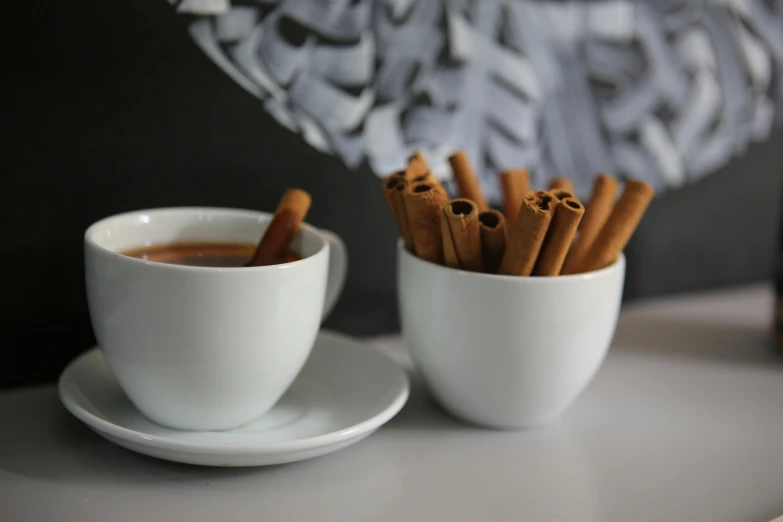 a cup of coffee with cinnamon sticks in it, pexels contest winner, antipodeans, grey, licorice allsort filling, product display photograph, two