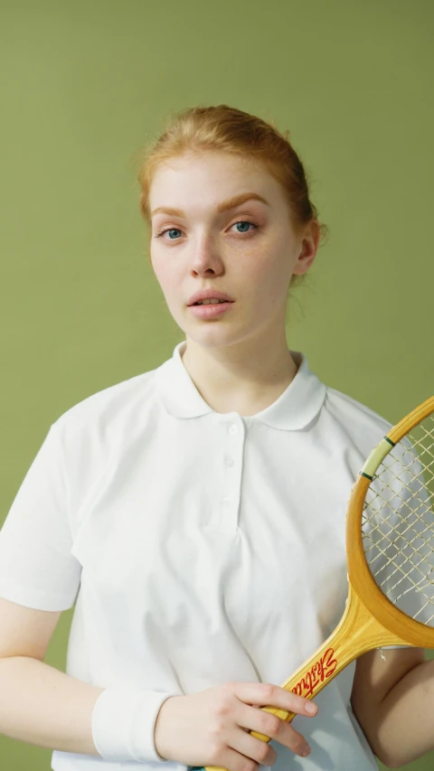 a woman holding a tennis racquet in one hand and a tennis ball in the other, an album cover, by Penelope Beaton, pexels contest winner, school uniform, eleanor tomlinson, white porcelain skin, sport t-shirt