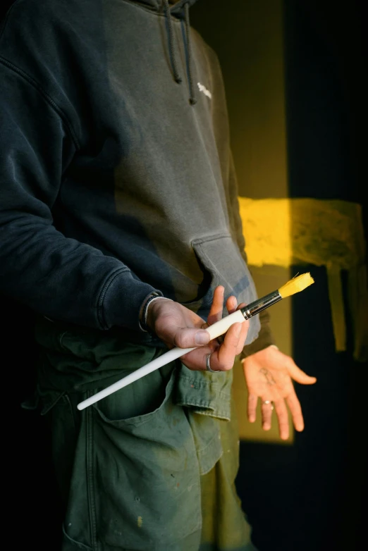 a man holding a knife in his right hand, a photorealistic painting, inspired by Hans Hartung, pexels contest winner, yellow broad sword, in a workshop, graphic detail, vandalism