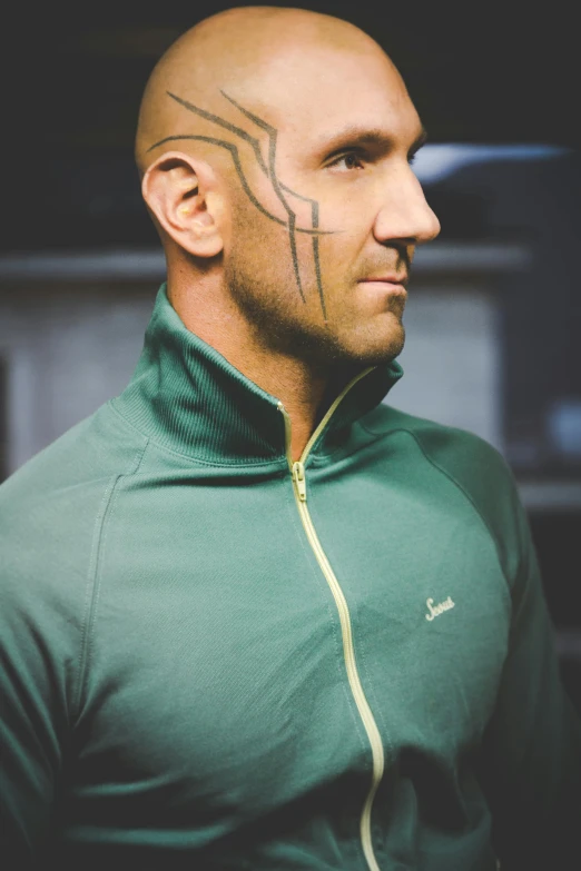 a man with a tattoo on his face, an album cover, inspired by Raphael, unsplash, wearing track and field suit, jason statham, casual green clothing, scribbled