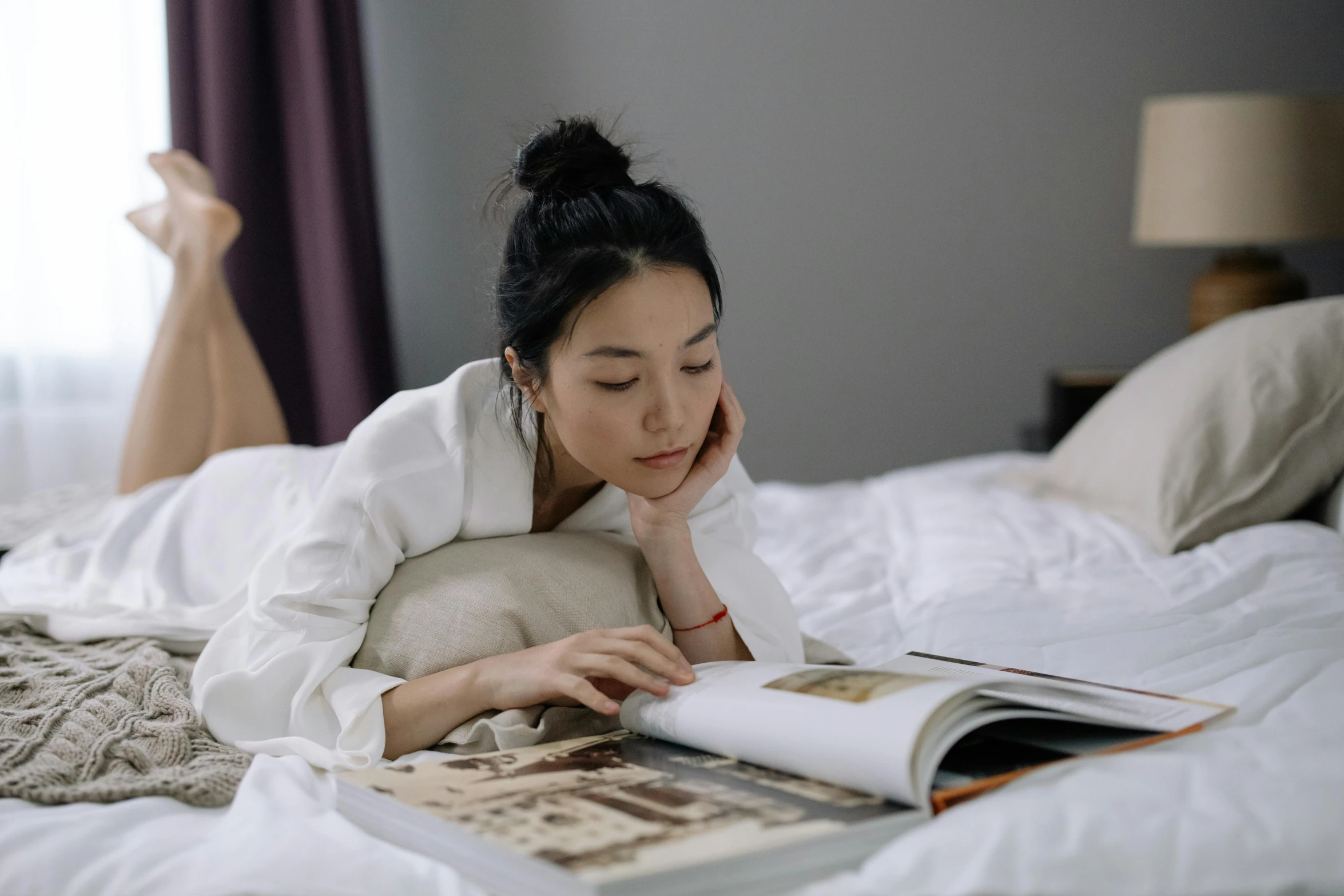 a woman laying on a bed reading a book, a drawing, by helen huang, pexels contest winner, happening, south korean male, smart looking, gif, white