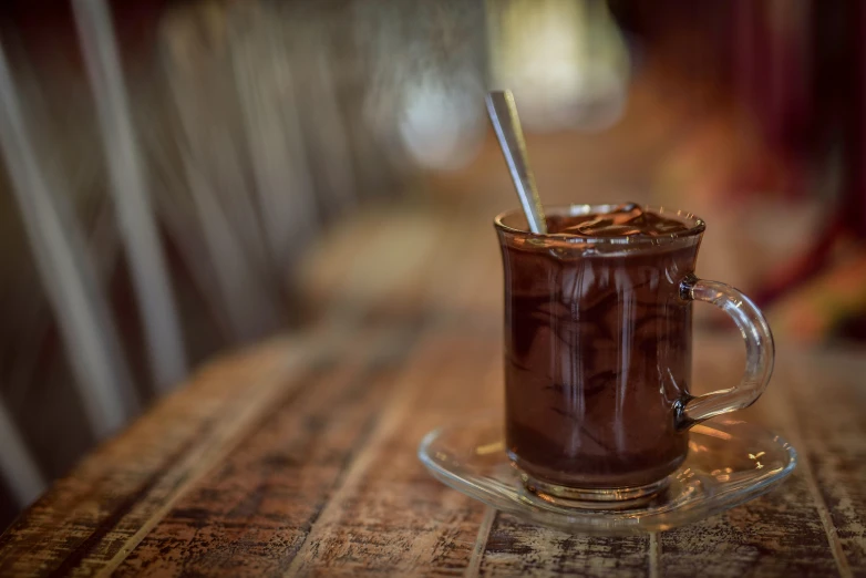 a cup of hot chocolate sitting on top of a wooden table, trapped in tall iced tea glass, liam brazier, coffee shop, thumbnail