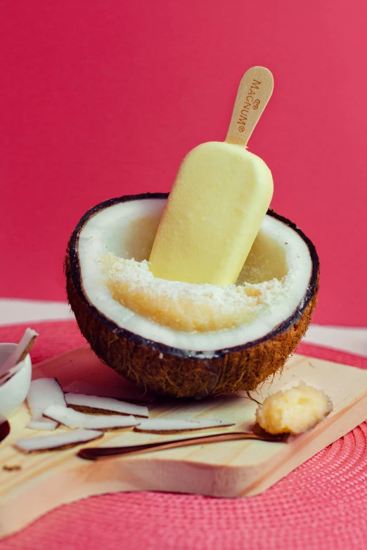 a popsicle sitting inside of a coconut shell on top of a cutting board, spoon, thumbnail, ivory, dessert