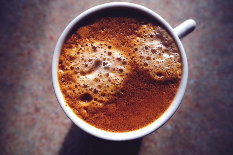 a close up of a cup of coffee on a table, pexels, foam, instagram photo, dark sienna and white, high-resolution