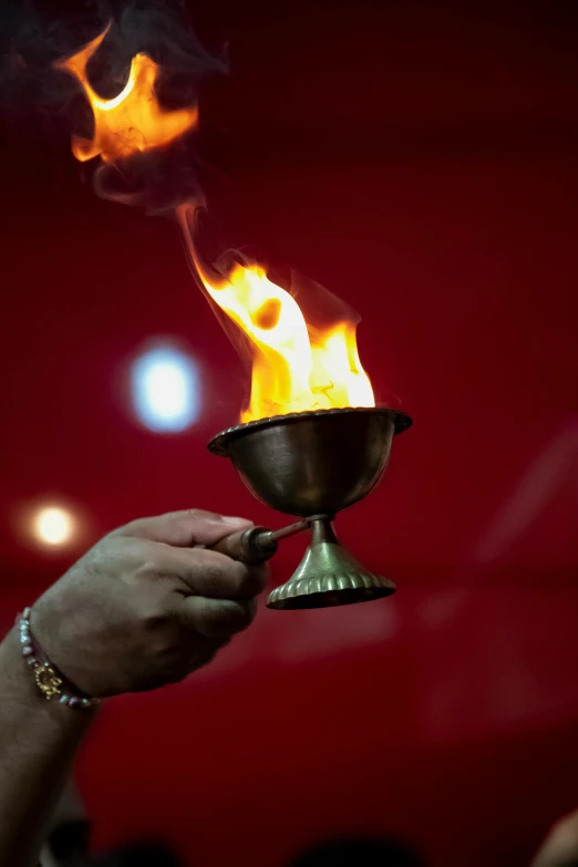 a person holding a lit candle in their hand, by Dan Content, trending on reddit, symbolism, olympics ceremony, overturned ornate chalice, nepal, wielding a fireball