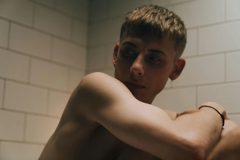 a shirtless young man sitting in a bathtub, an album cover, inspired by Kyle Lambert, trending on pexels, standing in a dimly lit room, caspar david, movie still 8 k, queer