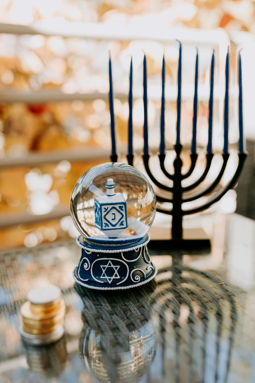 a snow globe sitting on top of a table next to a candelab, by Julia Pishtar, fine art, hebrew, geometric ornament, navy, holiday vibe