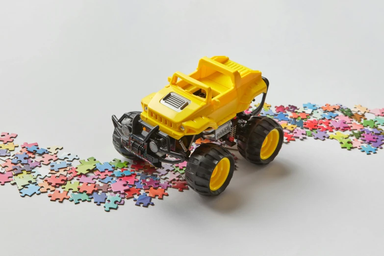 a toy truck sitting on top of a pile of puzzle pieces, on a yellow paper, off-roading, mechanised, no logo