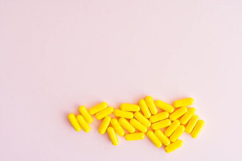 a pile of yellow pills on a pink background, by Nicolette Macnamara, pexels, on a white table, hyperminimalist, strokes, 🐿🍸🍋