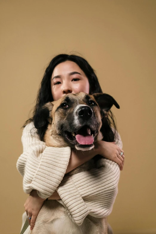 a woman holding a dog in her arms, pexels contest winner, portrait of mulan, plain background, janice sung, caramel