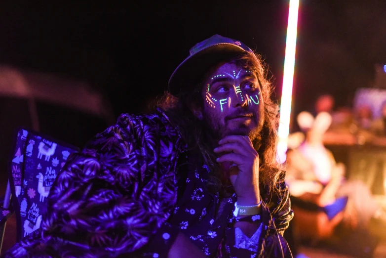 a man with face paint holding a microphone, unsplash, glow sticks, raver girl, contemplating, shpongle