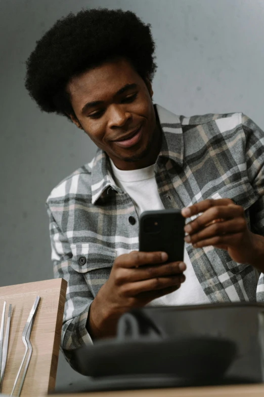 a man sitting at a table looking at his cell phone, trending on pexels, renaissance, wearing a flannel shirt, afro tech, thumbnail, gray men