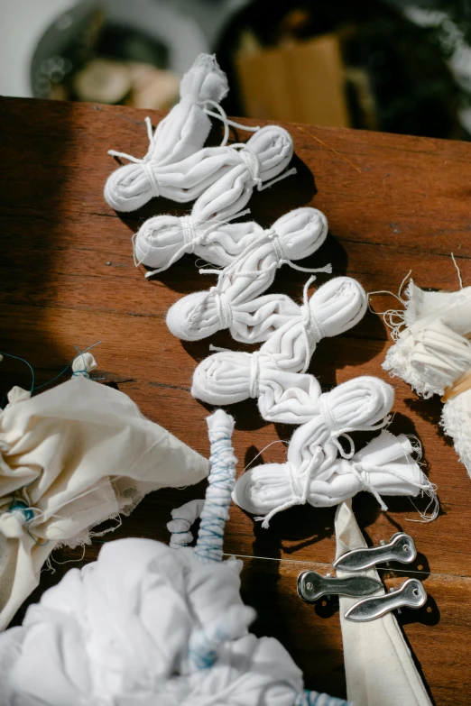 a bunch of white yarn sitting on top of a wooden table, by Jessie Algie, process art, bones joints, ai robot tendril remnants, super detail of each object, discarded scrolls