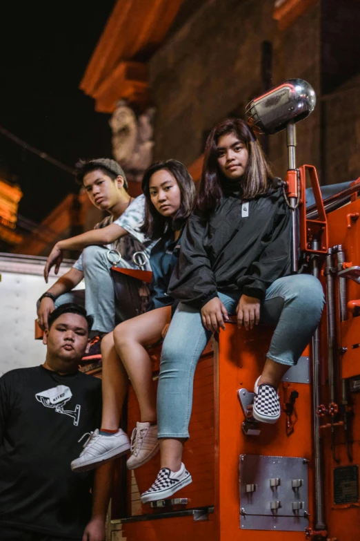 a group of people sitting on top of a truck, by Jack C. Mancino, pexels contest winner, she is wearing streetwear, cindy avelino, studio photoshot, predawn