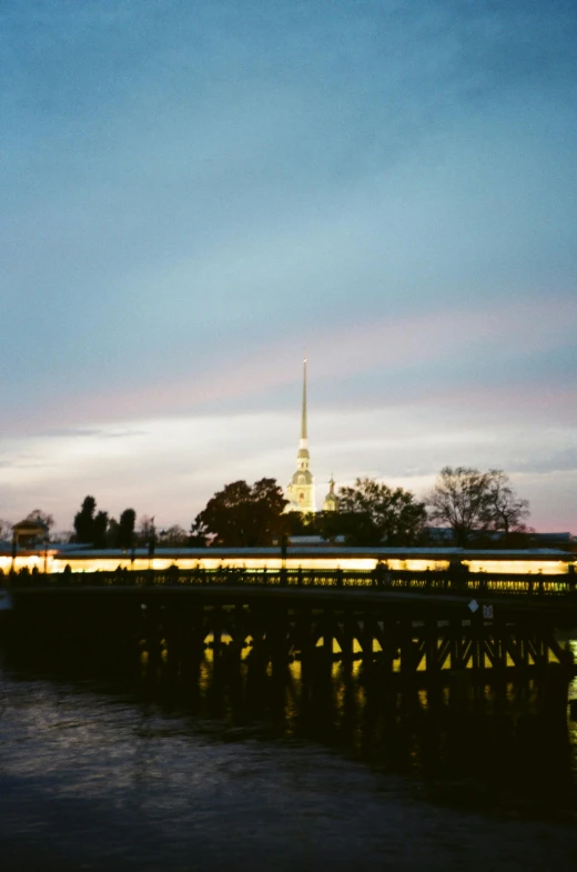 a bridge over a body of water with a clock tower in the background, inspired by Fyodor Vasilyev, unsplash, f 1.4 kodak portra, evening sky, lead - covered spire, saint petersburg