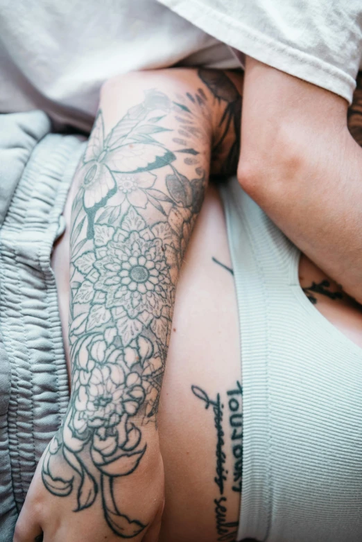 a close up of a person with tattoos on their arms, couple on bed, upper and lower body, laying down, intricate photo