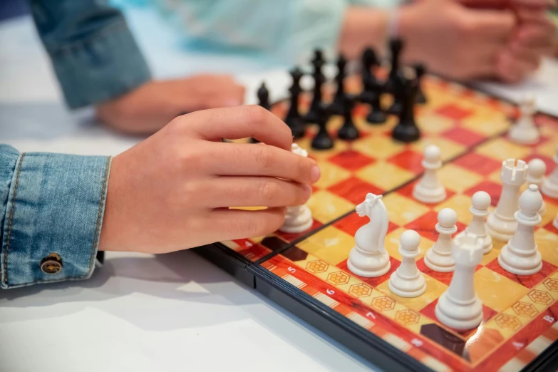 two people playing a game of chess on a table, zoomed in, multicoloured, kids playing, white: 0.5