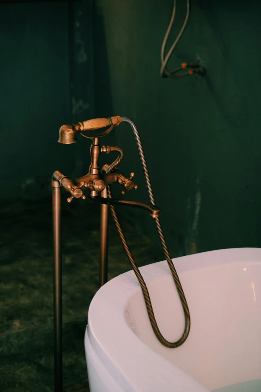 a bath tub sitting in a bathroom next to a faucet, unsplash, art nouveau, rusty pipes, glamping, gold plated, julian ope