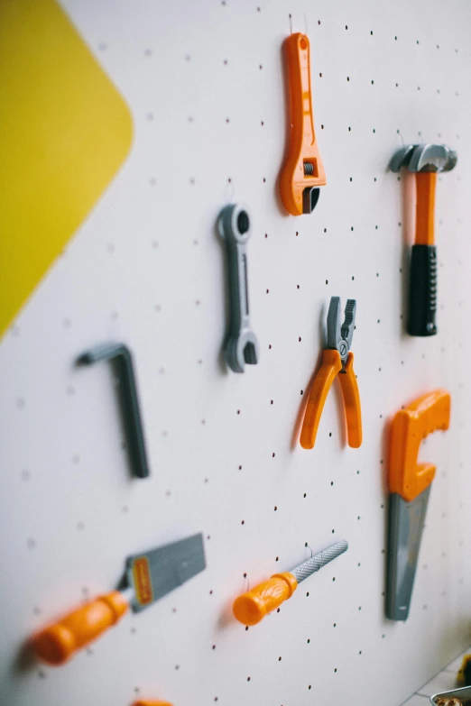 a close up of a bunch of tools on a wall, inspired by Rube Goldberg, pexels contest winner, magnetic, orange grey white, polka dot, 3d printed