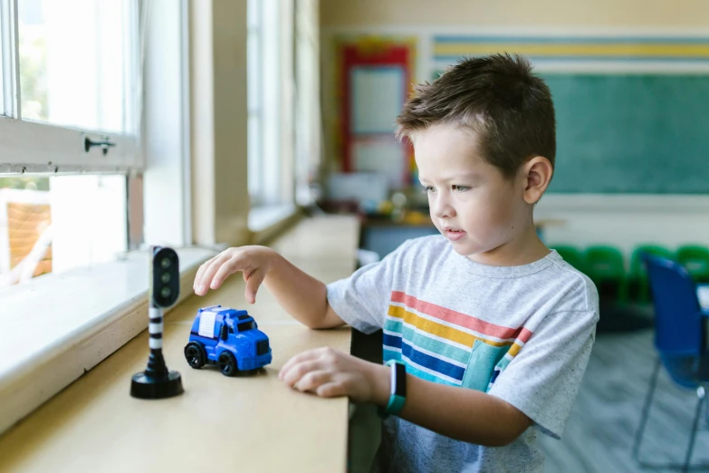 a young boy playing with a toy truck, pexels contest winner, visual art, robotic prosthetic arm, samsung smartthings, game and watch, school curriculum expert