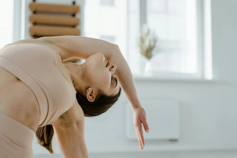 a woman doing a yoga pose in front of a window, trending on pexels, arabesque, bending over, manuka, head and shoulder shot, colour photograph