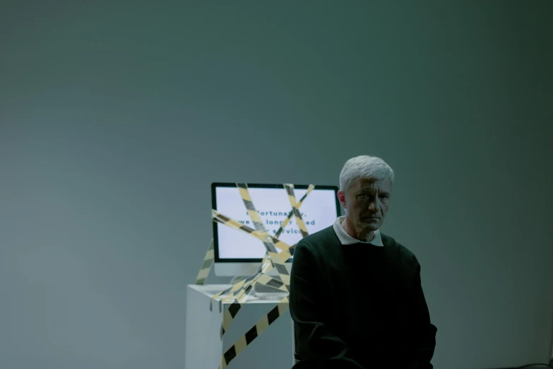 a man sitting in front of a computer monitor, by Attila Meszlenyi, video art, peter eisenman, nadav kander, on a pedestal, worksafe. cinematic