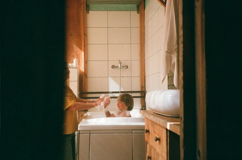 a woman washing a child in a bathtub, inspired by Elsa Bleda, pexels contest winner, still from a wes anderson movie, in a cabin, heath clifford, 3 4 5 3 1