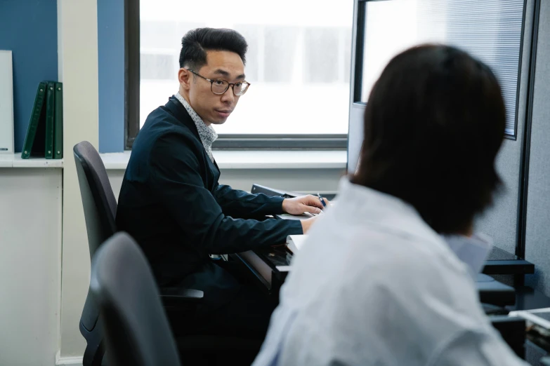 a man sitting at a desk in front of a computer, jordan grimmer and natasha tan, business meeting, slight overcast, colour corrected