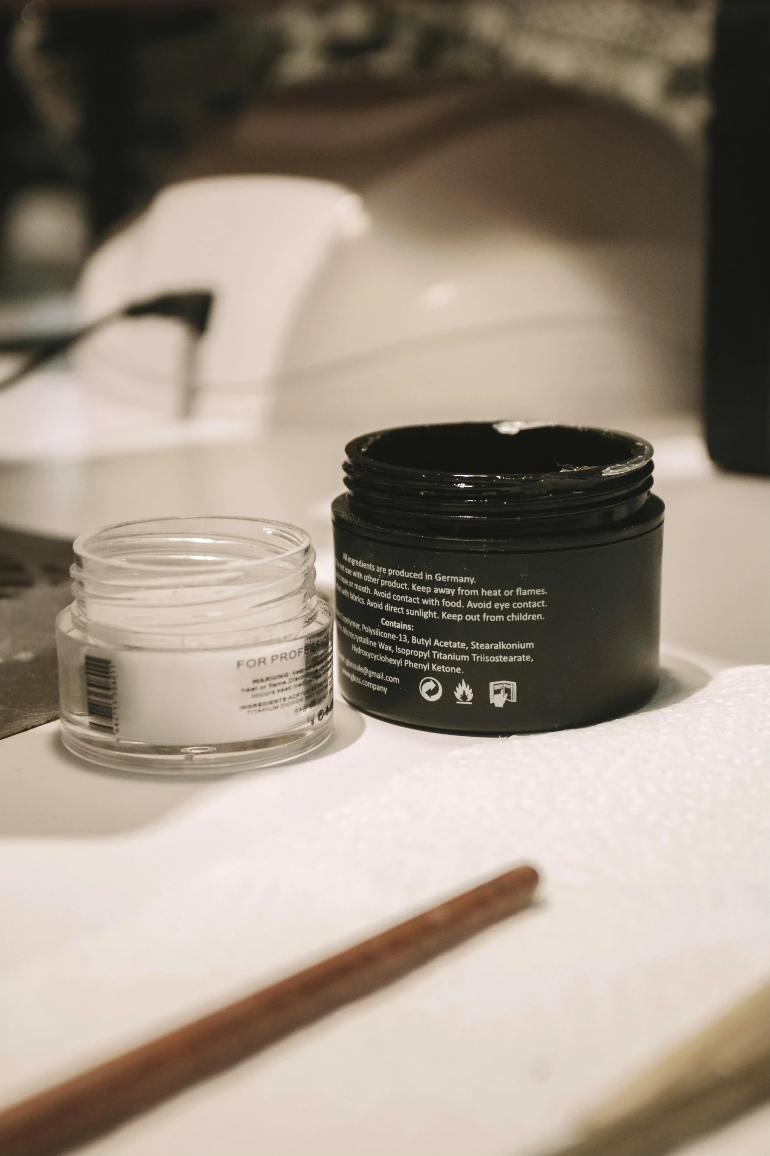 a close up of a jar of cream on a table, a black and white photo, unsplash, synthetic bio skin, black mask, manicured, high light on the left