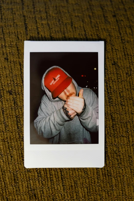 a polaroid picture of a man wearing a red hat, a polaroid photo, inspired by Seb McKinnon, mac miller, middle finger, teddy fresh, long night cap