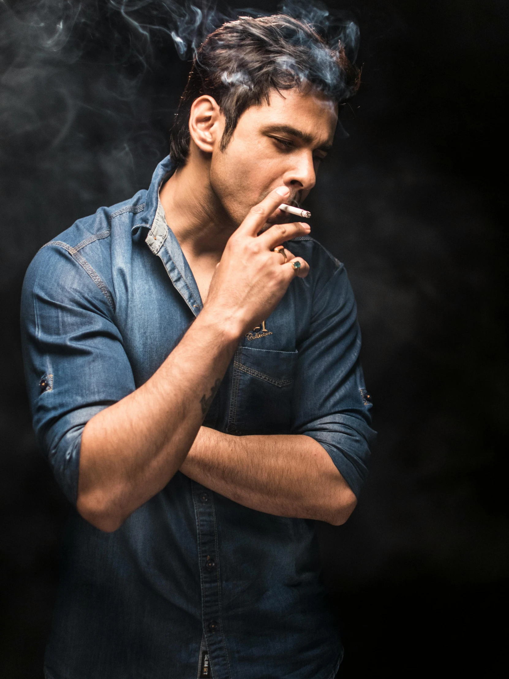 a man smoking a cigarette in a dark room, an album cover, inspired by Adam Dario Keel, pexels contest winner, indian super model, casual pose, a handsome, smoke :6