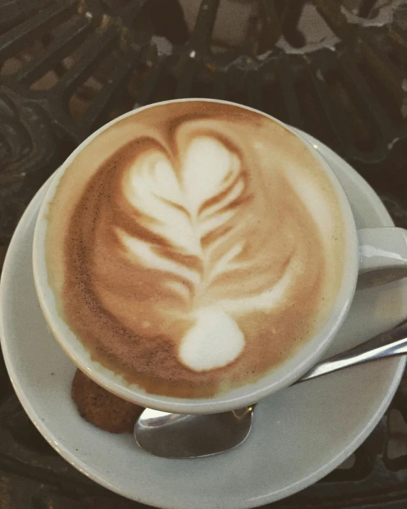 a cup of coffee sitting on top of a saucer, heart - shaped face, light tan, swirly, thumbnail