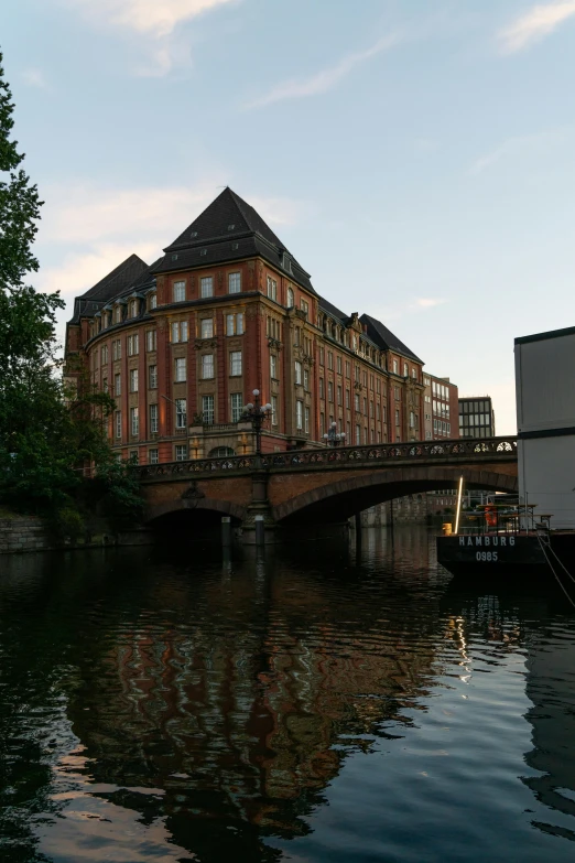 a bridge over a body of water with a building in the background, heidelberg school, tenement buildings, beautifully lit, canals, taken in 2022