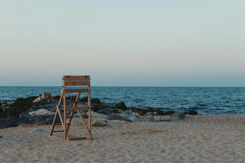 a wooden chair sitting on top of a sandy beach, by Elsa Bleda, pexels contest winner, realism, watch tower, brown, rectangle, summer evening