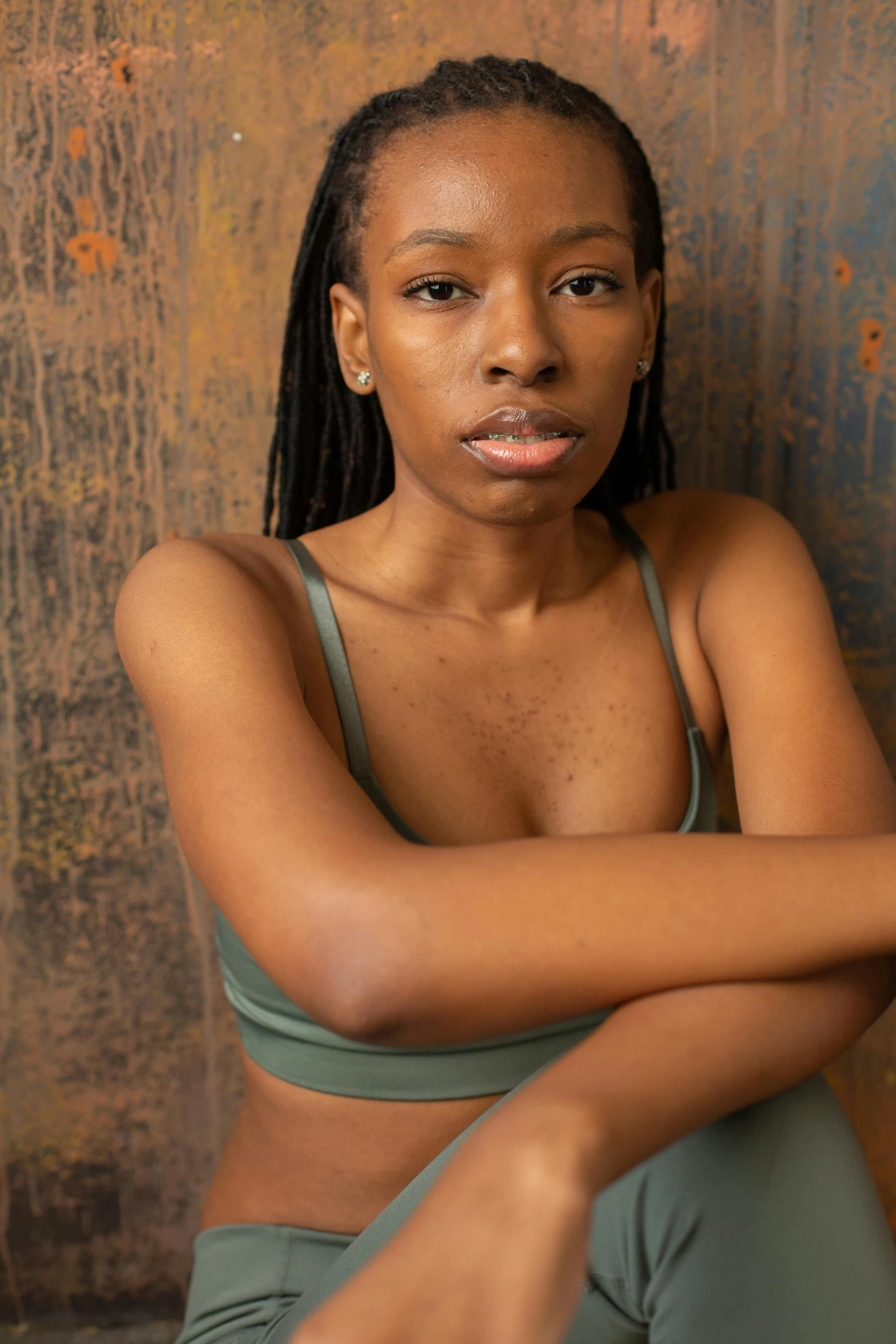 a beautiful young woman sitting on top of a wooden floor, by Lily Delissa Joseph, her belly button is exposed, riyahd cassiem, portrait photo of a backdrop, proud serious expression