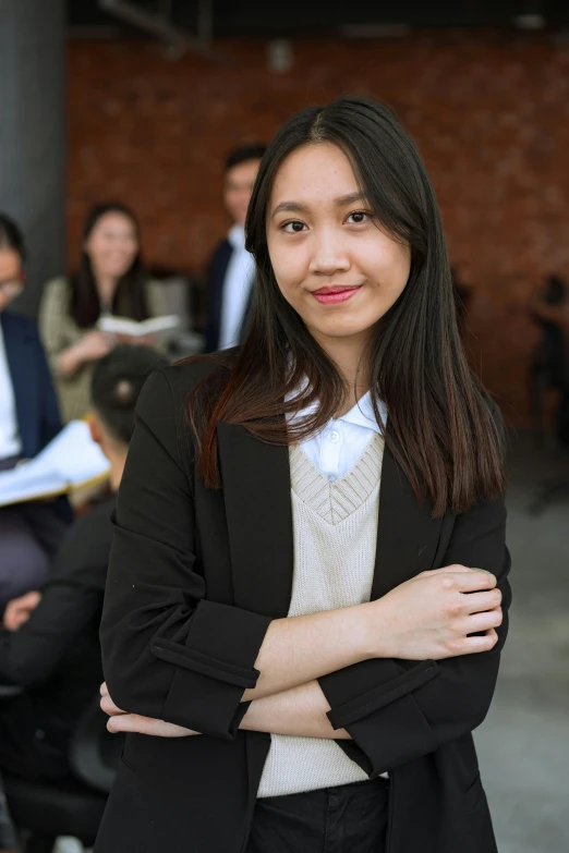 a woman standing in front of a group of people, wearing a black blazer, young asian woman, lawyer clothing, promo image