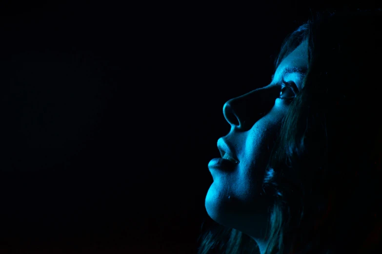 a close up of a person in a dark room, looking up to the sky, profile image, blue backlight, young woman's face