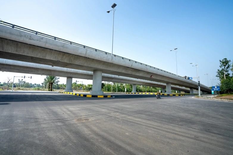 a man riding a skateboard down a street next to a bridge, hurufiyya, empty road in the middle, under construction, listing image, square