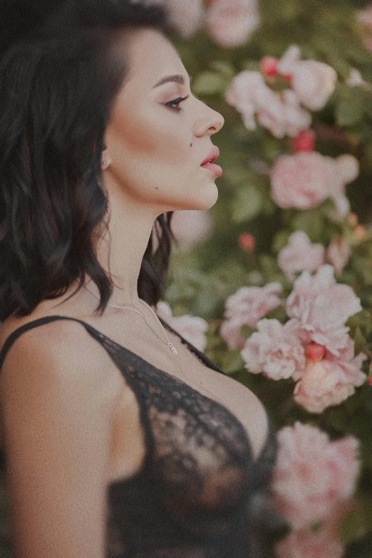 a woman standing in front of a bush of flowers, inspired by Hedi Xandt, trending on pexels, arabesque, very sexy woman with black hair, laced lingerie, profile image, close up half body shot