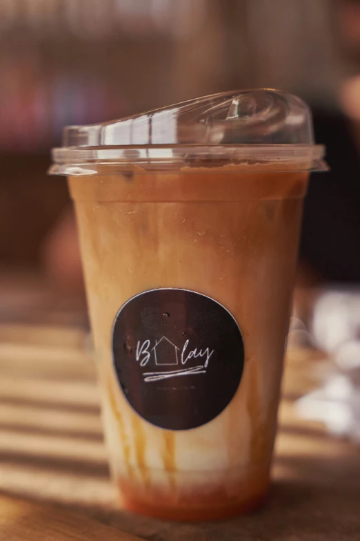 a close up of a cup of coffee on a table, iced latte, binkley, thumbnail, slay